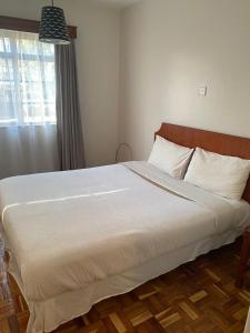 內羅畢的住宿－Capital Apartments- Hendred Road，卧室配有一张带白色床单的大床和窗户。
