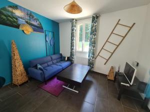 a living room with a blue couch and a table at Maison Cosy en Pleine Nature 