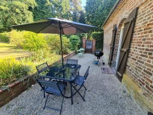 uma mesa e cadeiras com um guarda-sol num pátio em Maison Cosy en Pleine Nature 