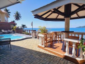 eine Terrasse mit einem Tisch, Stühlen und einem Sonnenschirm in der Unterkunft The Drake Seaside Apartment in Bel Ombre