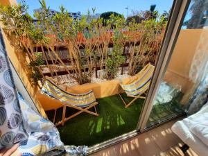 einen Balkon mit Blick auf zwei Stühle und Pflanzen in der Unterkunft Appartement en Résidence avec piscine proche mer in Le Barcarès