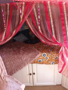 - un lit avec rideau rouge et tapis dans l'établissement Git'an Périgord la Bonne aventure, à Groléjac