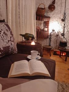 un libro abierto sentado en un sofá con una taza de café en Sailor's Rustic House en Virpazar