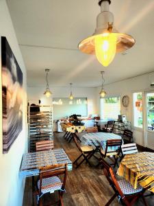una sala de estar con mesas, sillas y una lámpara de araña. en Hôtel Land'Azur en Mimizan-Plage