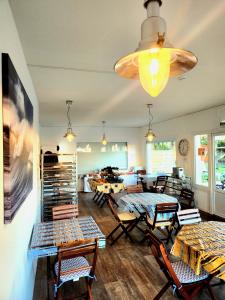 a living room with tables and chairs and a chandelier at Hôtel Land'Azur in Mimizan-Plage