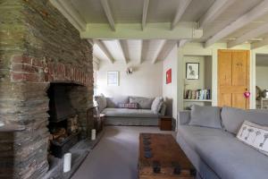 a living room with a couch and a stone fireplace at 18th Century Primrose Cottage in Chillington nr sea 