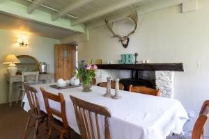 a dining room with a white table with chairs and a fireplace at 18th Century Primrose Cottage in Chillington nr sea 