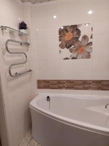 a bathroom with a tub and a picture of flowers on the wall at Apartments on Kharkovskaya Street in Sumy