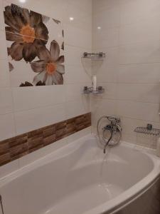 a white tub in a bathroom with a painting on the wall at Apartments on Kharkovskaya Street in Sumy