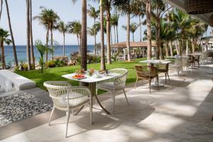 a patio with tables and chairs and the ocean at Hotel Fariones in Puerto del Carmen