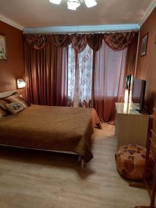 a bedroom with a bed and a television and curtains at Apartments on Kharkovskaya Street in Sumy