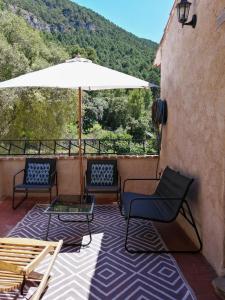 a patio with two chairs and an umbrella at Apartamentos Mas de Pau in Fuentespalda