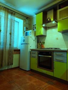 a kitchen with green cabinets and a white refrigerator at Apartments on Kharkovskaya Street in Sumy