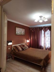 a bedroom with a bed with red walls and a window at Apartments on Kharkovskaya Street in Sumy