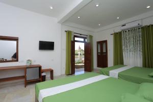 a bedroom with two beds and a desk and a television at Green Shield Resort in Anuradhapura