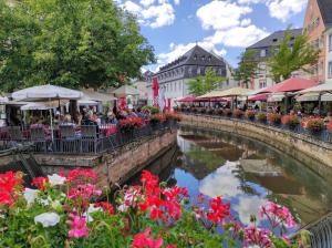 a group of people sitting at tables near a river with flowers at Gästehaus Hoxel in Hoxel