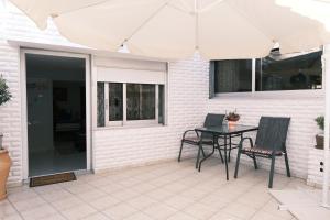 eine Terrasse mit einem Tisch, Stühlen und einem Sonnenschirm in der Unterkunft CHEZ KYRIAKI in Kavala