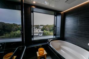 a bathroom with a bath tub and two windows at Ise-Shima Ohtaya Healing Stay in Toba