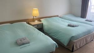 Dos camas en una habitación de hotel con toallas. en Olympic Inn Kanda, en Tokio