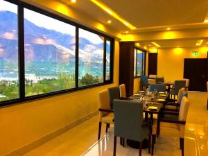 a dining room with a table and chairs and large windows at Avari Xpress Gilgit in Gilgit