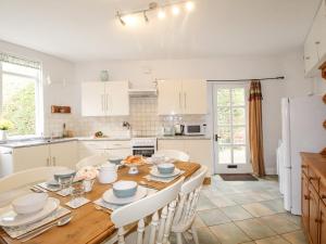 una cucina e una sala da pranzo con tavolo e sedie in legno di Vine Cottage a Studland