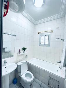 a bathroom with a toilet and a tub and a sink at Appartement Rapha'ella Meublé in Yaoundé