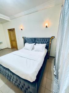 1 cama con sábanas blancas y almohadas en una habitación en Appartement Rapha'ella Meublé en Yaundé