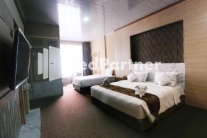 a hotel room with two beds and a tv at Edotel Syariah Nilam Sari Mitra RedDoorz in Pekanbaru