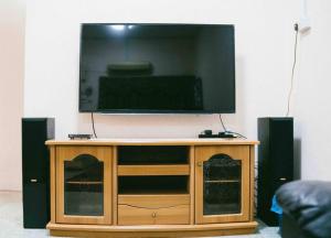 a flat screen tv on top of a wooden entertainment center at # J Homestay [15PAX -4ROOM-TOWN AREA] in Melaka