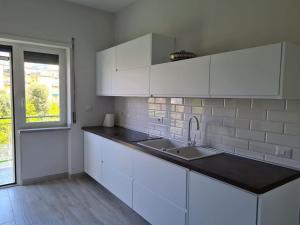 uma cozinha com armários brancos, um lavatório e uma janela em casa pagliara em Sorrento