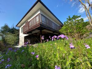 uma casa com varanda num campo de flores em Nikko PRIVATE INN WA NODOKA em Nikko