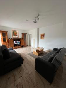 a living room with two black couches and a tv at Shivas Ferienwohnung in Goch