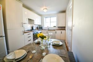 a kitchen with a table with plates and flowers on it at Einstein House Horizon Stays in Stockton-on-Tees
