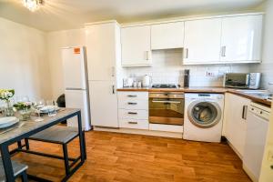 uma cozinha com armários brancos, uma mesa e uma máquina de lavar roupa em Einstein House Horizon Stays em Stockton-on-Tees
