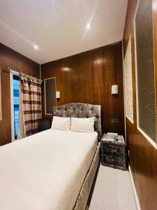 Cheshire Hotel Central London في لندن: غرفة نوم بسرير كبير وجدران خشبية
