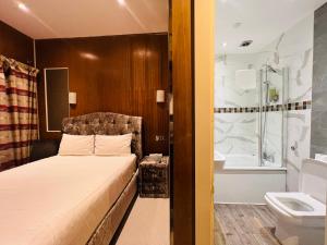 Cheshire Hotel Central London في لندن: غرفة نوم بسرير وحوض استحمام ومغسلة