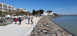 a group of people walking on a sidewalk next to the water at Grand studio chaleureux à Port Neuf in La Rochelle