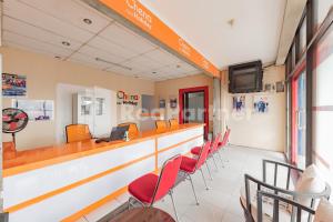 a waiting room with red chairs and a counter at 158 Guest House Syariah RedPartner in Bandung