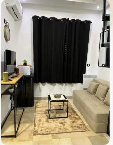 sala de estar con sofá y cortina negra en Appartement Cosy aux Jardins de Carthage, en Sidi Daoud