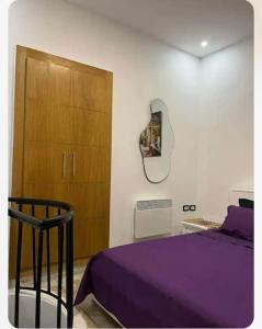 a bedroom with a purple bed and a wooden cabinet at Appartement Cosy aux Jardins de Carthage in Sidi Daoud