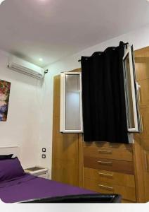 1 dormitorio con cama morada y ventana en Appartement Cosy aux Jardins de Carthage en Sidi Daoud