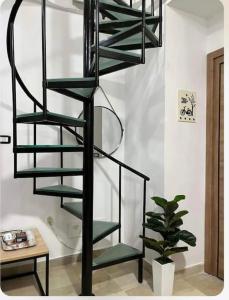 a black spiral staircase in a room with a plant at Appartement Cosy aux Jardins de Carthage in Sidi Daoud
