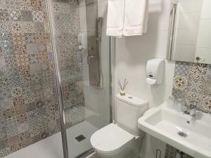 a bathroom with a toilet and a shower and a sink at Baixo a Lua Rooming in Sarria