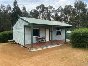 ein kleines weißes Haus mit einer Veranda und einem Tisch in der Unterkunft Manyat Peak cottages in Porongurup