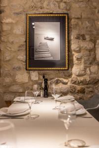 uma mesa com copos de vinho e uma fotografia numa parede de pedra em Leonis Restaurant & Rooms em Split