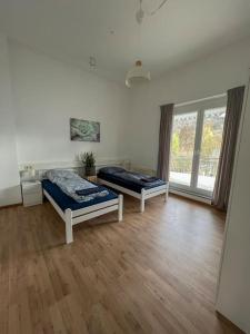 two beds in a room with a wooden floor at Modernes Apartment mit Balkon, Parkplatz und Smart Tv bis zu 10 Personen in Weinstadt