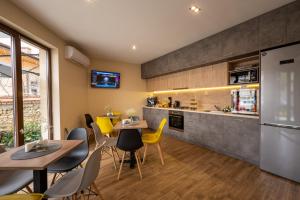 a kitchen and dining room with tables and yellow chairs at Семеен Хотел Константинови in Kyustendil