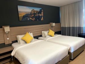 a hotel room with two beds with yellow pillows at Le cassia Hotel in Khon Kaen