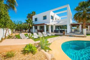 a large white house with a swimming pool and chairs at Villa Athos - PlusHolidays in Calpe