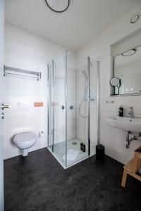 a bathroom with a shower and a toilet and a sink at Limehome Bremerhaven Kantstraße in Bremerhaven +21 photos